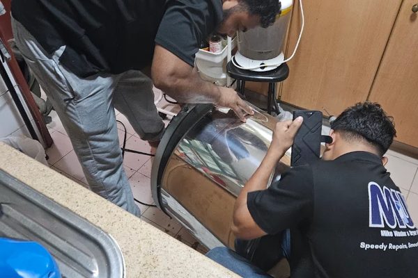 Two of our technicians on a front-load washing machine in a kitchen