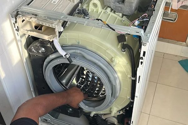 Working under an opened front loader to reach the drum and motor