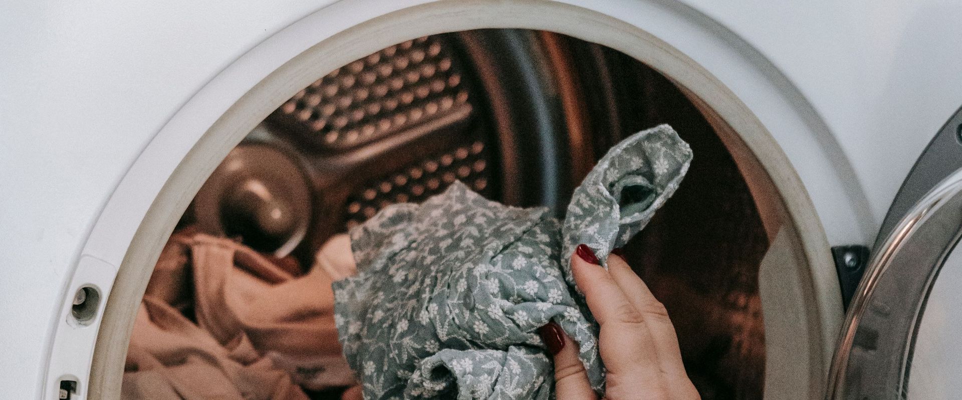 Hands loading laundry into a dryer