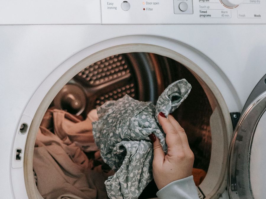 Hands loading laundry into a dryer