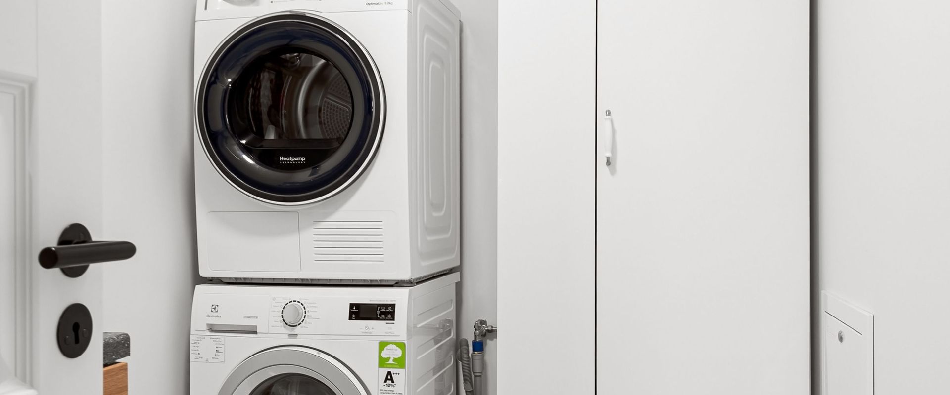 Stacked washer and dryer installed in a white laundry closet
