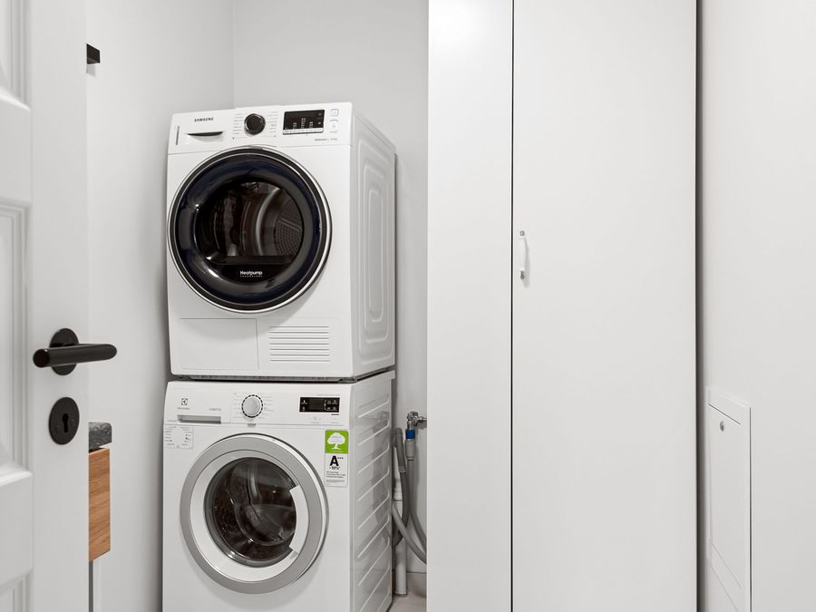 Stacked washer and dryer installed in a white laundry closet