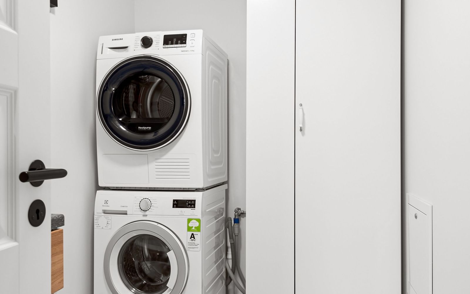 Stacked washer and dryer installed in a white laundry closet