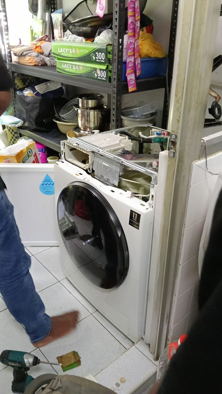 Technician from Mike Washer & Dryer Services servicing a front-load washing machine at a customer's home