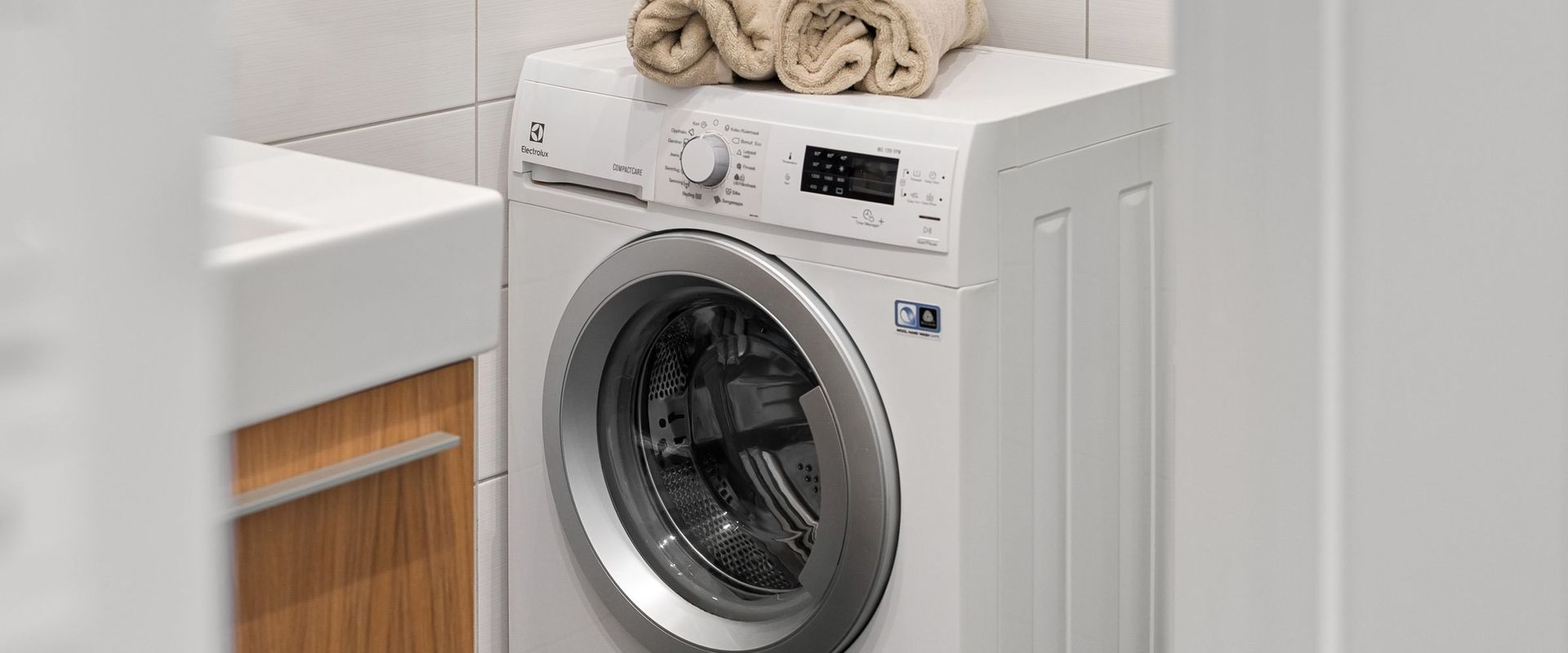 White front-load washing machine with folded towels on top