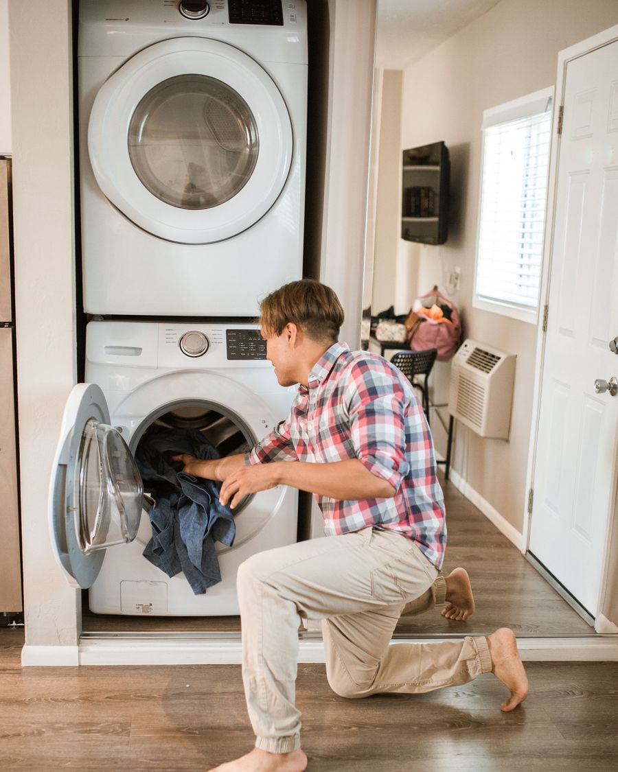 Man loading clothes into a front-load washing machine at home