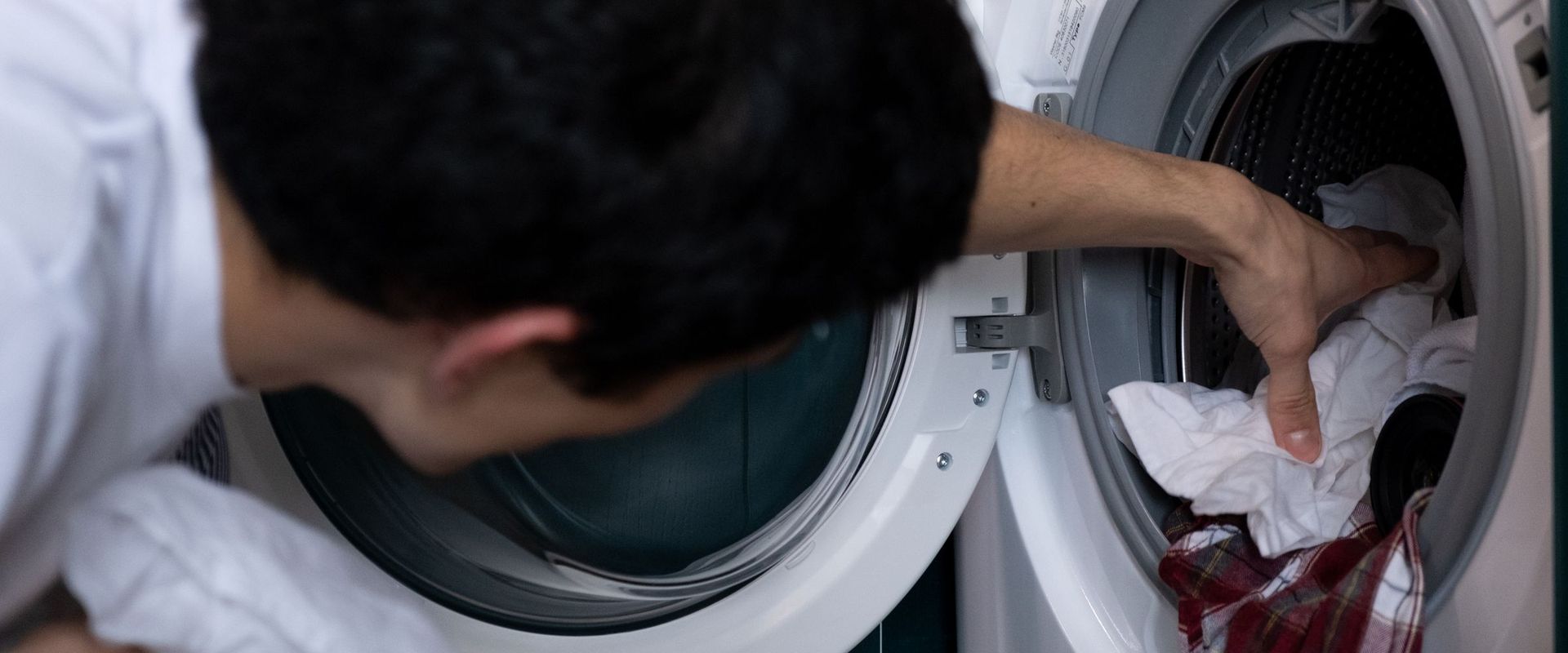 Man loading clothes into a front-load washing machine at home